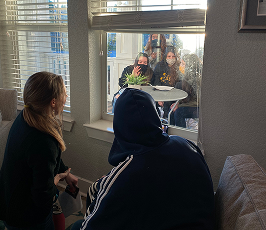 SAGU students speaking with Daymark residents through the window meeting